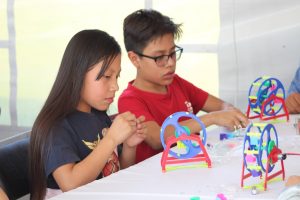 Niño y niña de CDMX en un taller del programa de robótica móvil de la AMC en la Noche de las Estrellas